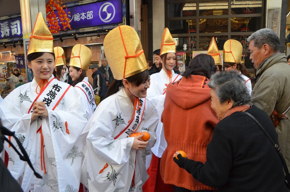 福もちとみかんを手渡し福を授けている写真