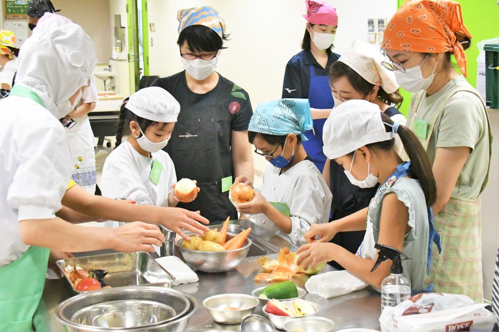 野菜を洗って皮を剥く児童たち