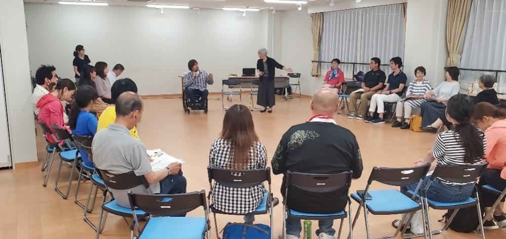 過去の車座ワークショップの様子。会議室で20人以上が輪になって椅子に座っている。