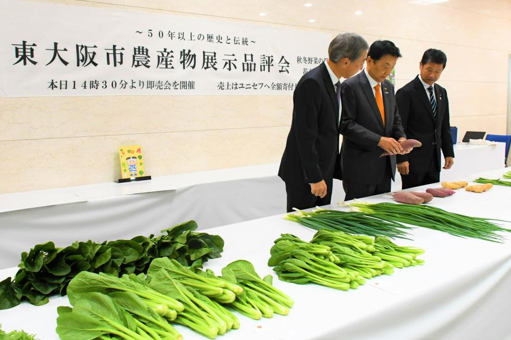 野田義和市長が東大阪産の農産物を手に取り、その出来栄えを確認している